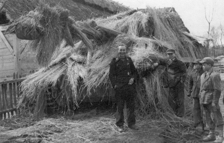 [Photo 10a - Pz Kpfw VI Tiger Ausf. E  heavily camouflaged by its crew with hay or straw next to a barn.]