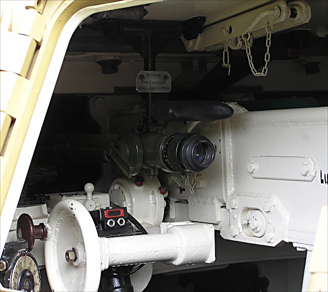 The gun sight on a Panzer III. I am uncertain of either the source of the image or the model of the Panzer III, but one can see through the open hatch, the conventional layout of the vehicle, in accordance with the Heer's standards during the war.